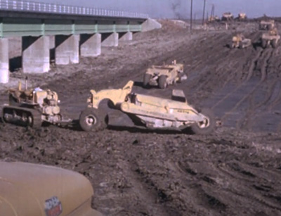 machines de construction creusant le sol devant un pont