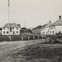 landscape of several wooden buildings and Red River carts in Fort Garry in 1875