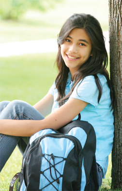 child sitting against a tree smiling