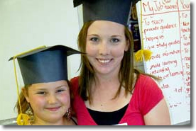 Female youth and child with graduation caps on